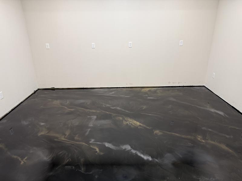 Finished black and charcoal metallic epoxy floor with gold swirl, high gloss