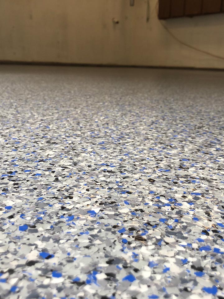 Close-up of vibrant blue, white, grey, and black flake floor finish
