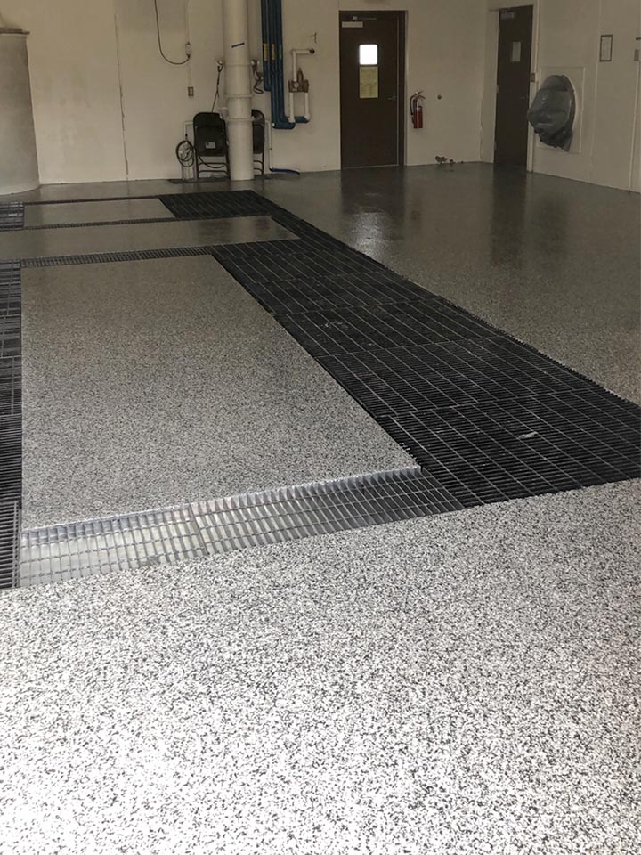 Industrial bay with grey flake floor and black metal trench-drain grates